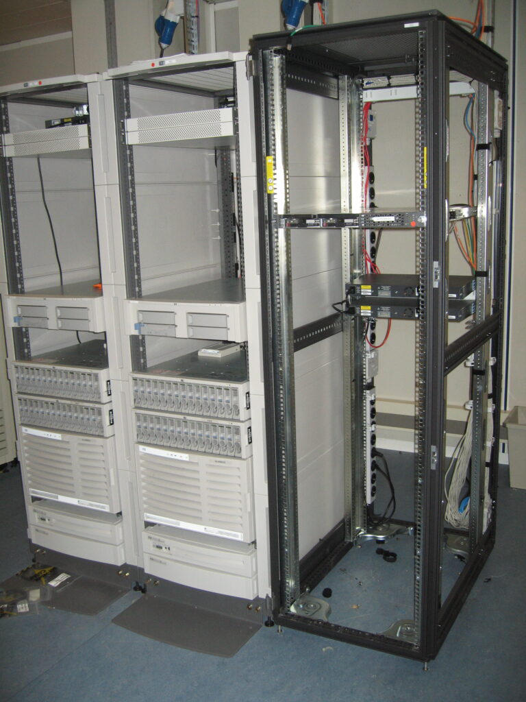 Mostly empty server racks with remaining equipment and cabling in a server room.