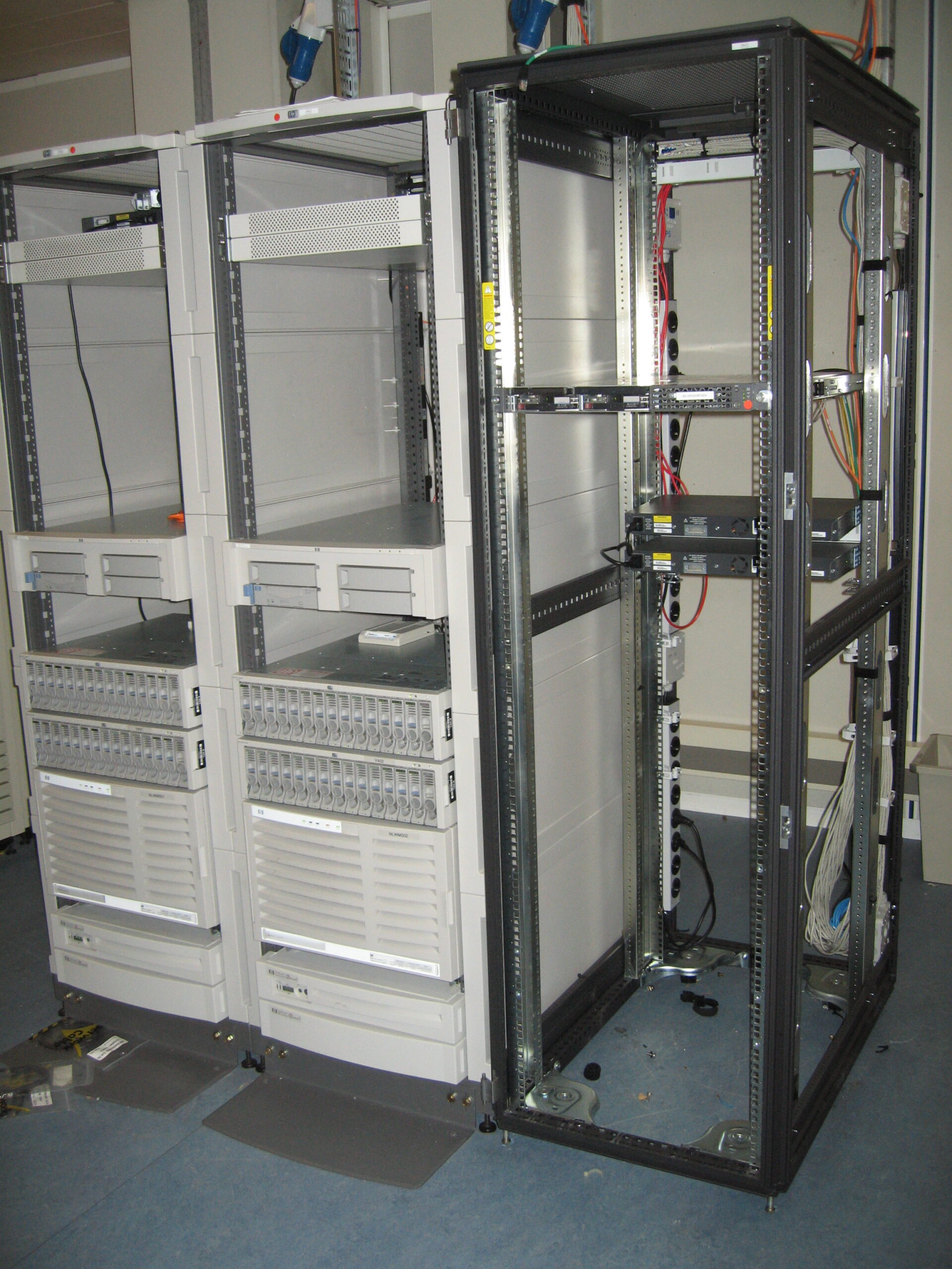 Mostly empty server racks with remaining equipment and cabling in a server room.
